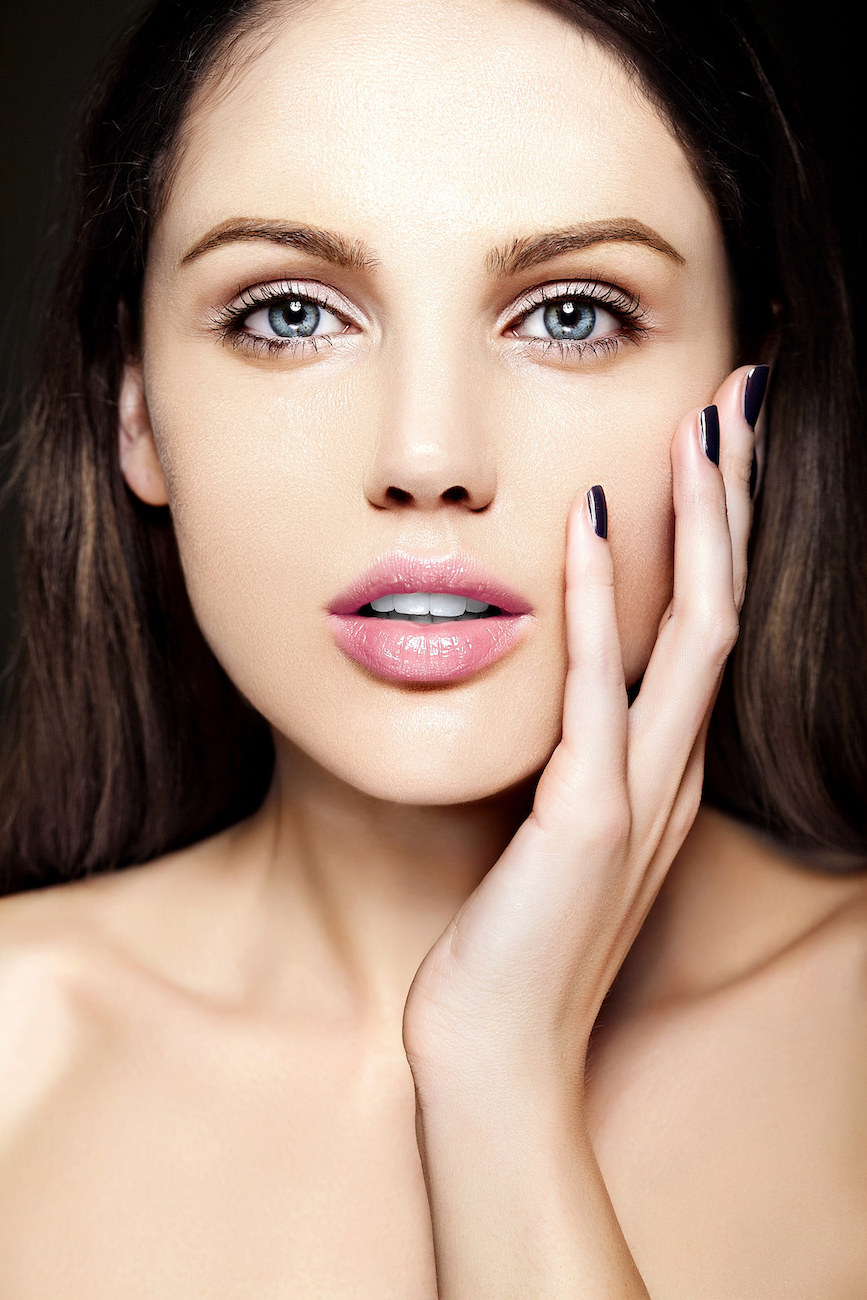 Close-up of a woman with smooth, radiant skin gently touching her face, highlighting clear complexion and youthful glow.